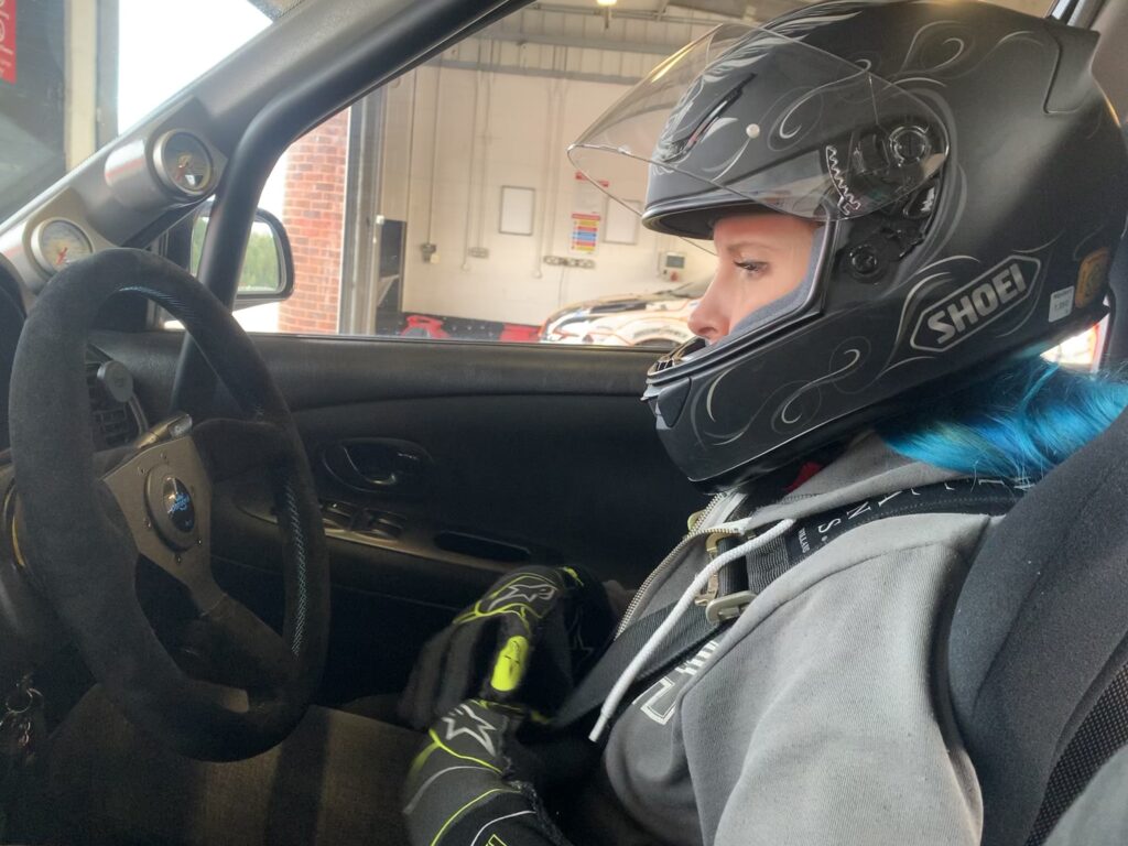 Woman in driver's seat of car with helmet on